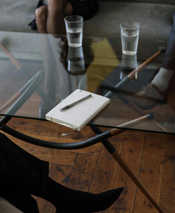 close up of a counseling session with two glasses of water and a notepad on a glass table
